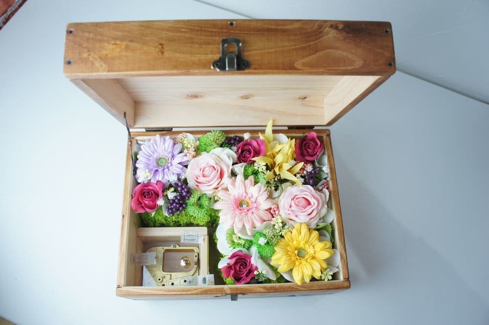 オルゴールBOXアレンジ　高級造花専門店アンクラフトは１級フラワー装飾技能士がアーティフィシャルフラワー（造花）を使用し、ご希望のアレンジメント、髪飾り、ブーケをオーダーメイドで制作致します。結婚記念日やお見舞いの花、花言葉に合わせたお花の贈り物や開店花、待合室用、応接用花、個性的な髪飾りや派手な花、大人可愛い、おしゃれなバラなどどんなオーダーでもお気軽にお問い合わせください。大阪、兵庫県、関西からアクセスが簡単。
